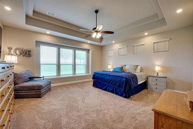 carpeted bedroom featuring ceiling fan and a raised ceiling