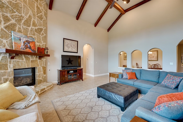 living room with beam ceiling, a stone fireplace, high vaulted ceiling, and ceiling fan