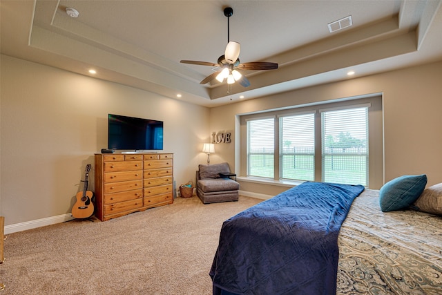 carpeted bedroom with ceiling fan and a raised ceiling