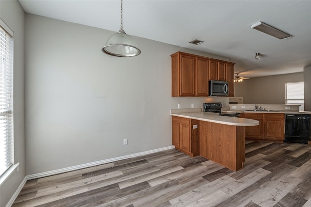 kitchen with black appliances, kitchen peninsula, light hardwood / wood-style floors, and plenty of natural light