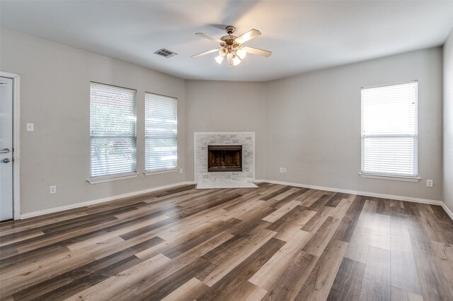 unfurnished living room with a healthy amount of sunlight, dark wood-type flooring, and ceiling fan