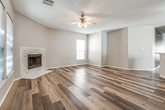 unfurnished living room with ceiling fan, wood-type flooring, and a fireplace