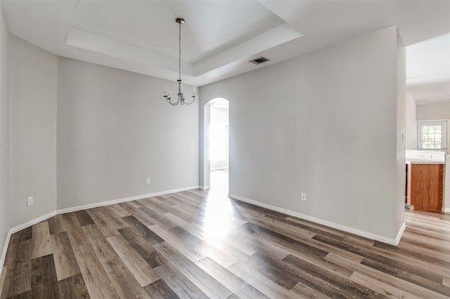 interior space featuring a notable chandelier, a raised ceiling, and hardwood / wood-style floors