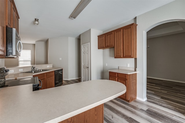 kitchen featuring sink, kitchen peninsula, stainless steel appliances, and light wood-type flooring