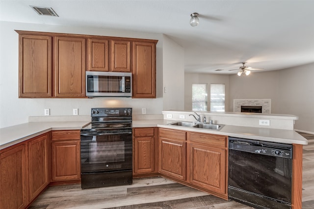 kitchen featuring kitchen peninsula, black appliances, sink, and light wood-type flooring