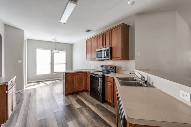 kitchen featuring sink, kitchen peninsula, stainless steel appliances, decorative light fixtures, and dark wood-type flooring