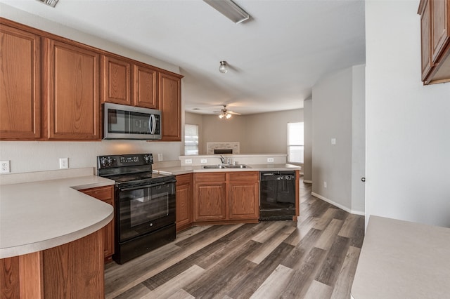 kitchen with black appliances, sink, kitchen peninsula, ceiling fan, and dark wood-type flooring