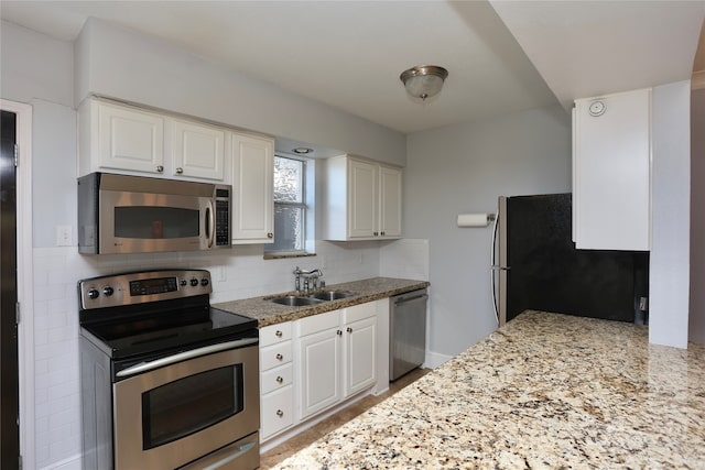 kitchen with light stone countertops, sink, appliances with stainless steel finishes, and white cabinets