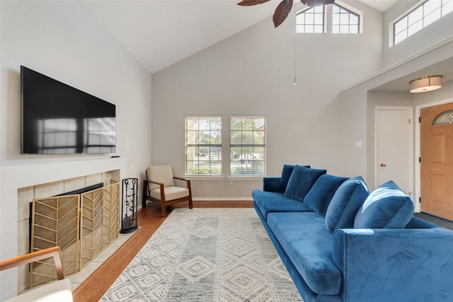 living room featuring ceiling fan, wood-type flooring, a fireplace, and high vaulted ceiling