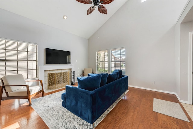 living room featuring a tile fireplace, ceiling fan, high vaulted ceiling, and hardwood / wood-style flooring