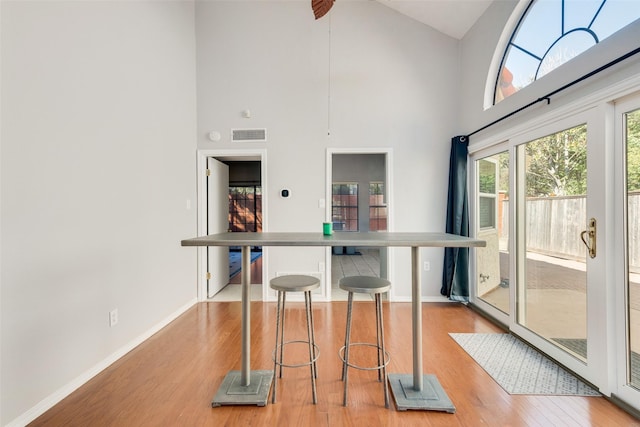 kitchen featuring light hardwood / wood-style floors, high vaulted ceiling, and a breakfast bar area