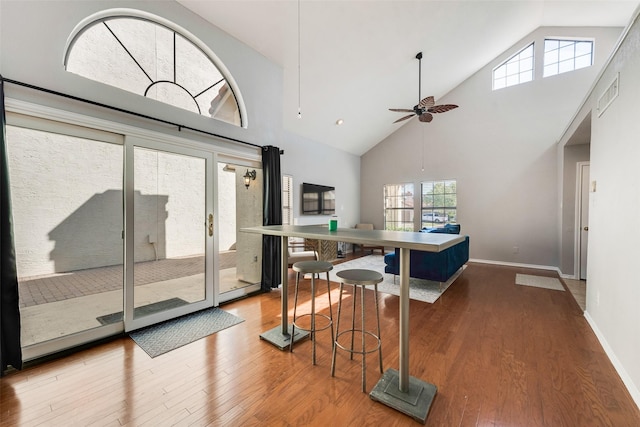 dining area featuring hardwood / wood-style floors, a towering ceiling, and ceiling fan