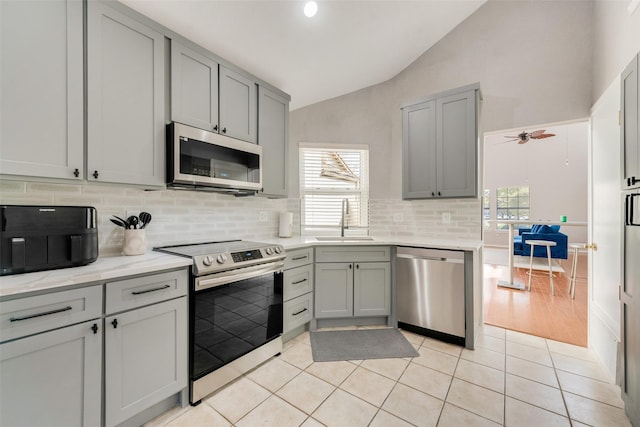 kitchen featuring appliances with stainless steel finishes, vaulted ceiling, ceiling fan, sink, and light tile patterned flooring