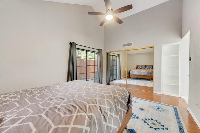 bedroom featuring ceiling fan, light hardwood / wood-style floors, high vaulted ceiling, and a closet