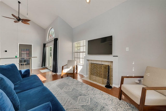 living room featuring a fireplace, light wood-type flooring, high vaulted ceiling, and ceiling fan