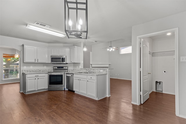 kitchen with white cabinets, ceiling fan, appliances with stainless steel finishes, dark hardwood / wood-style floors, and decorative light fixtures