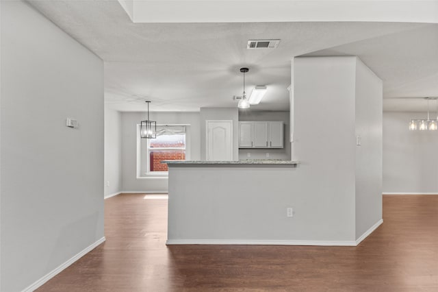 kitchen with kitchen peninsula, dark wood-type flooring, and pendant lighting