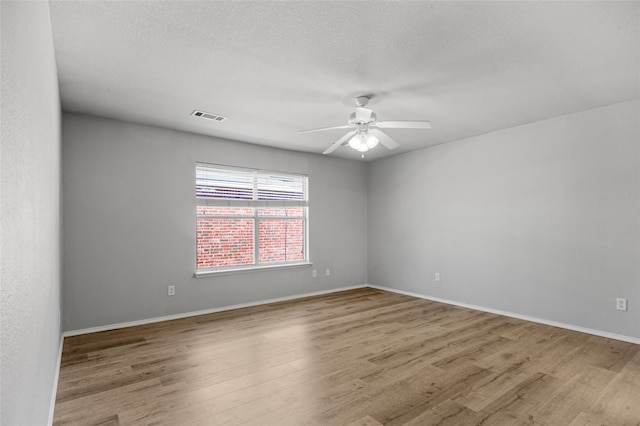 empty room featuring light hardwood / wood-style flooring, a textured ceiling, and ceiling fan