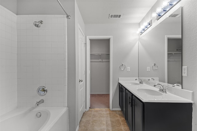 bathroom featuring tiled shower / bath, vanity, a textured ceiling, and tile patterned floors