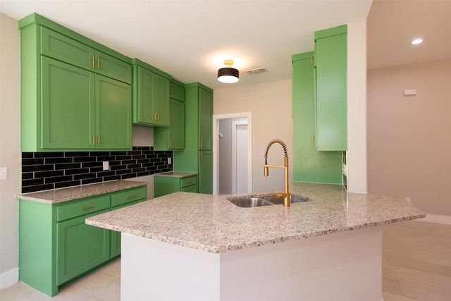 kitchen with kitchen peninsula, light stone countertops, sink, and green cabinetry