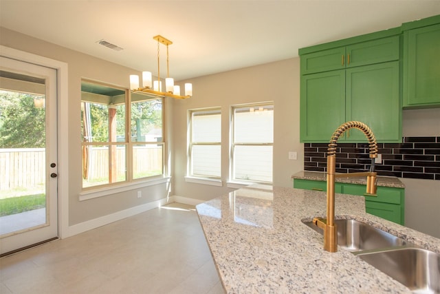 kitchen with sink, decorative light fixtures, light stone countertops, and green cabinets