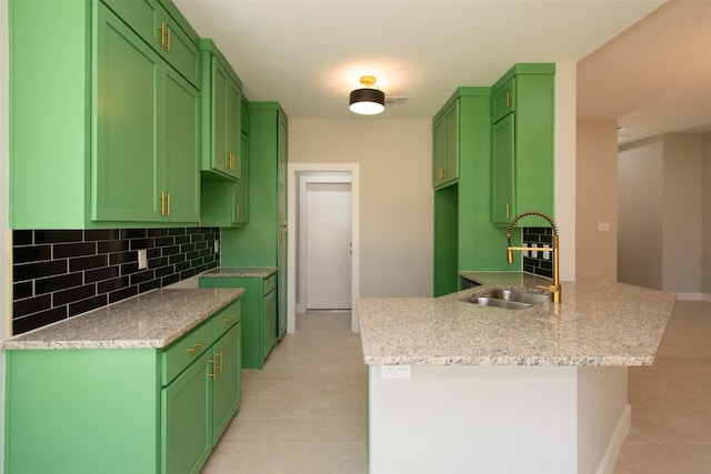 kitchen with tasteful backsplash, light stone countertops, sink, and green cabinetry