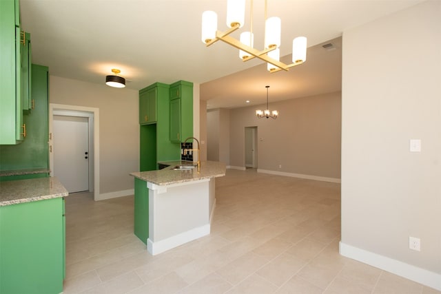 kitchen with sink, green cabinets, a notable chandelier, light stone countertops, and decorative light fixtures