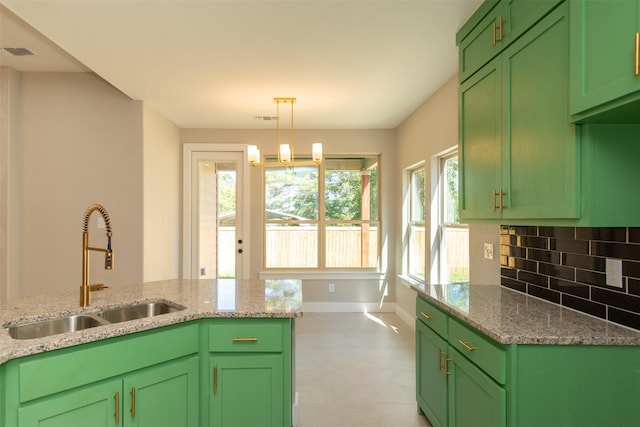 kitchen featuring light stone countertops, sink, backsplash, and green cabinetry