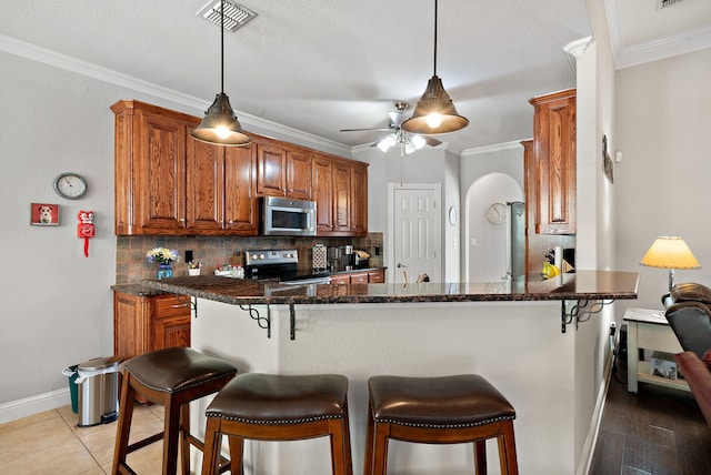 kitchen with tasteful backsplash, appliances with stainless steel finishes, a breakfast bar, and kitchen peninsula