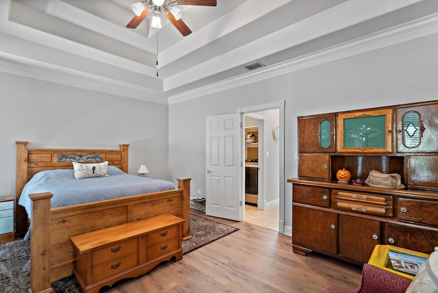 bedroom featuring light hardwood / wood-style flooring, ornamental molding, a raised ceiling, and ceiling fan