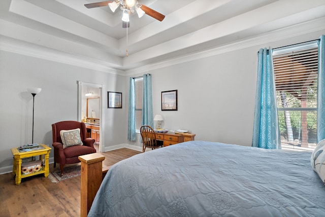 bedroom with ceiling fan, hardwood / wood-style flooring, a raised ceiling, and ensuite bath