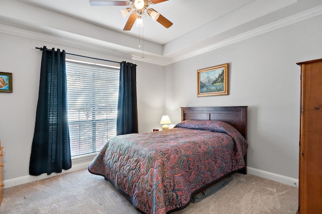 carpeted bedroom with ornamental molding, a raised ceiling, and ceiling fan