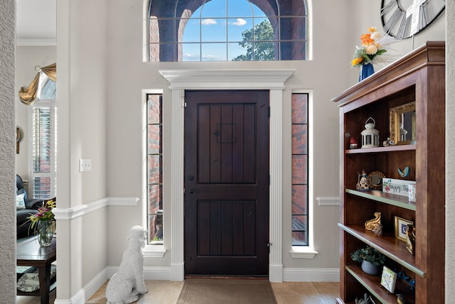 entryway featuring ornamental molding and light tile patterned flooring