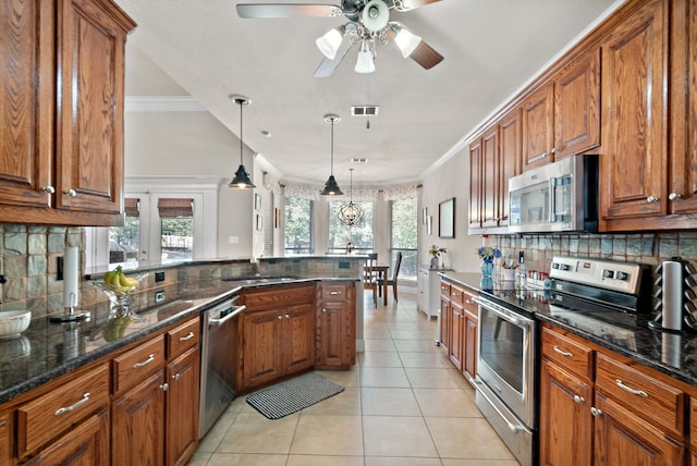 kitchen featuring tasteful backsplash, hanging light fixtures, appliances with stainless steel finishes, light tile patterned flooring, and crown molding