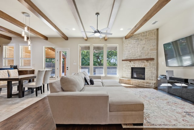 living room with beamed ceiling, plenty of natural light, ceiling fan, and a fireplace