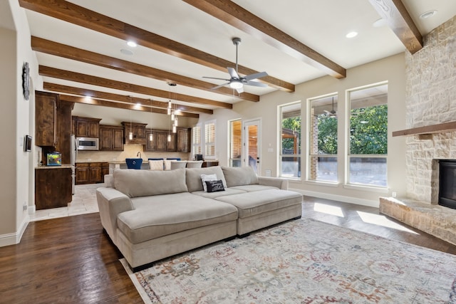 living room with beam ceiling, ceiling fan, a fireplace, and dark wood-type flooring