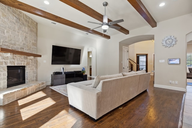 living room featuring beamed ceiling, dark hardwood / wood-style flooring, a fireplace, and ceiling fan