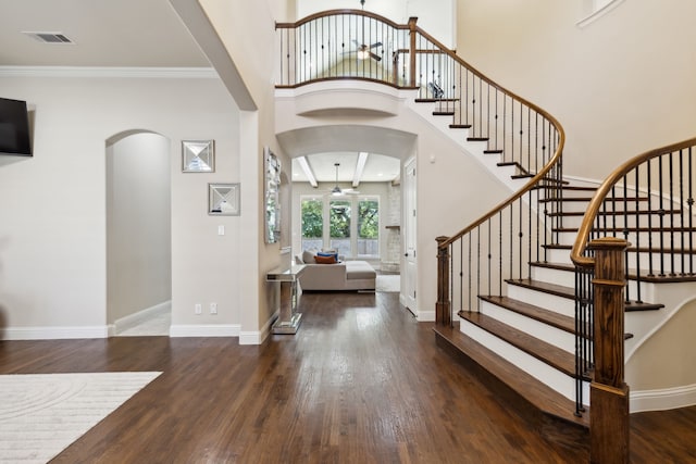 foyer with ceiling fan, crown molding, a towering ceiling, and dark wood-type flooring