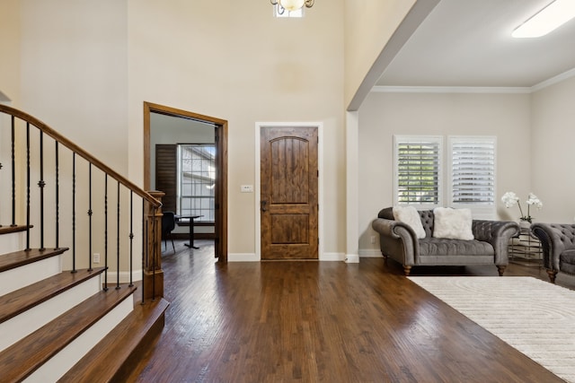 foyer featuring ornamental molding, dark wood-type flooring, and a high ceiling