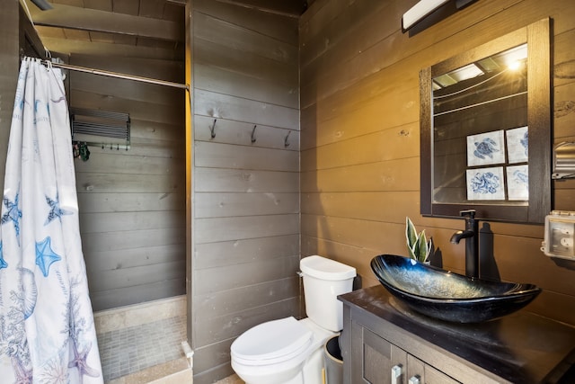 bathroom featuring vanity, wood walls, toilet, and walk in shower