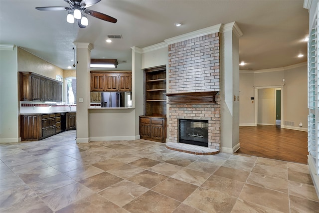 unfurnished living room featuring crown molding, decorative columns, a brick fireplace, and ceiling fan