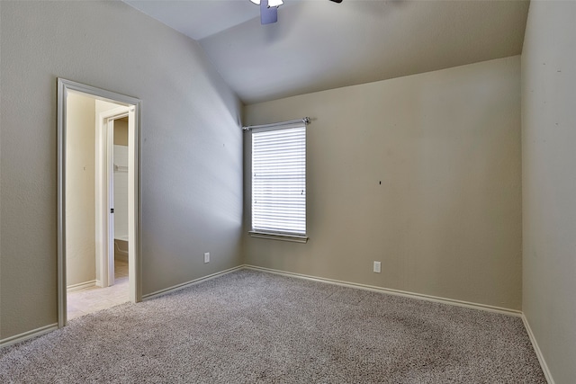 carpeted spare room with ceiling fan and vaulted ceiling