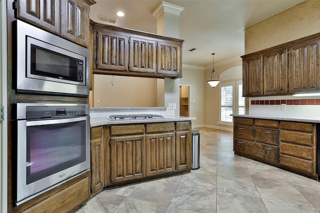 kitchen with tasteful backsplash, hanging light fixtures, appliances with stainless steel finishes, light stone countertops, and crown molding