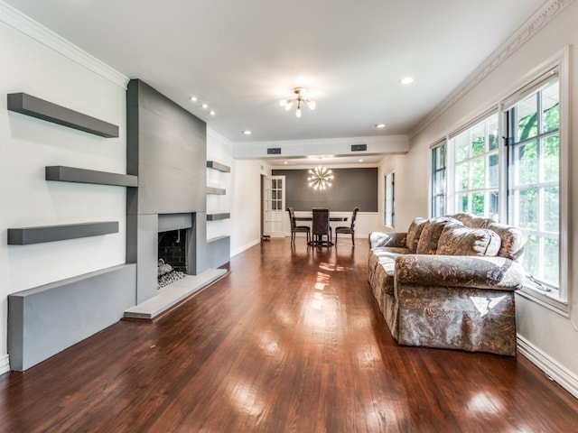 living room with crown molding, dark hardwood / wood-style flooring, a chandelier, and a fireplace