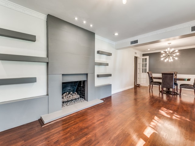 living room with ornamental molding, dark hardwood / wood-style floors, a chandelier, and a fireplace