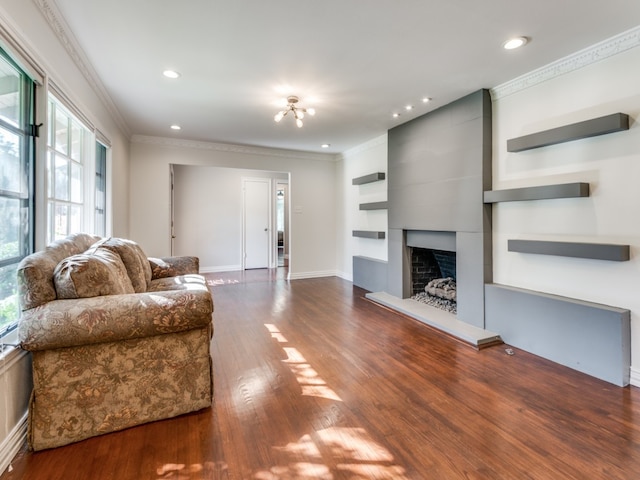 living room with crown molding, hardwood / wood-style floors, and a large fireplace