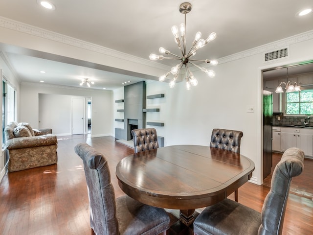 dining room with ornamental molding, hardwood / wood-style flooring, a chandelier, and sink