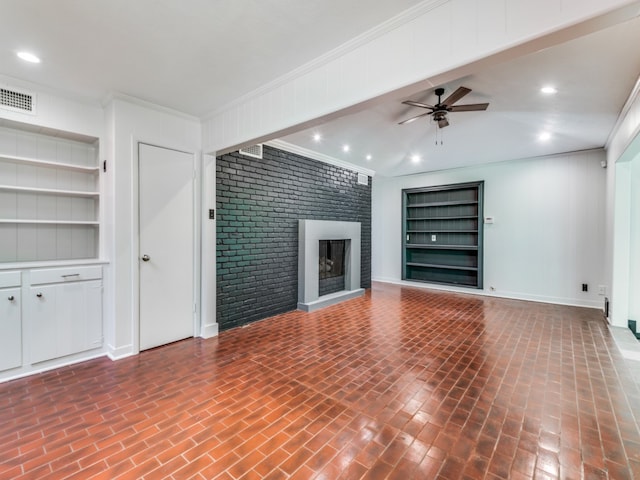 unfurnished living room featuring built in shelves, crown molding, a fireplace, and ceiling fan