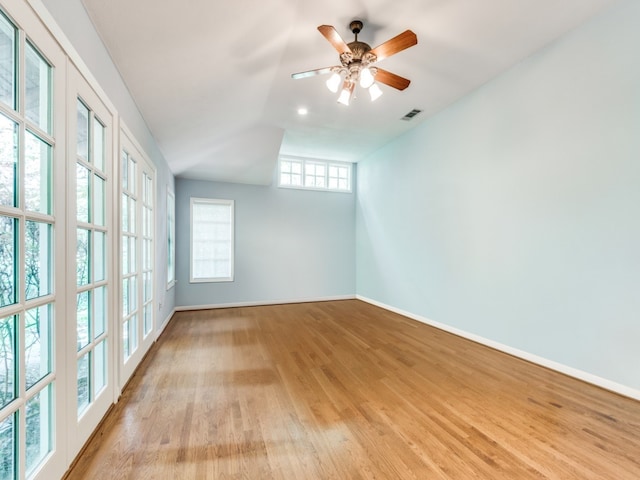 empty room featuring lofted ceiling, french doors, light wood-type flooring, and ceiling fan