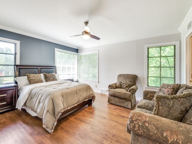 bedroom with crown molding, multiple windows, wood-type flooring, and ceiling fan